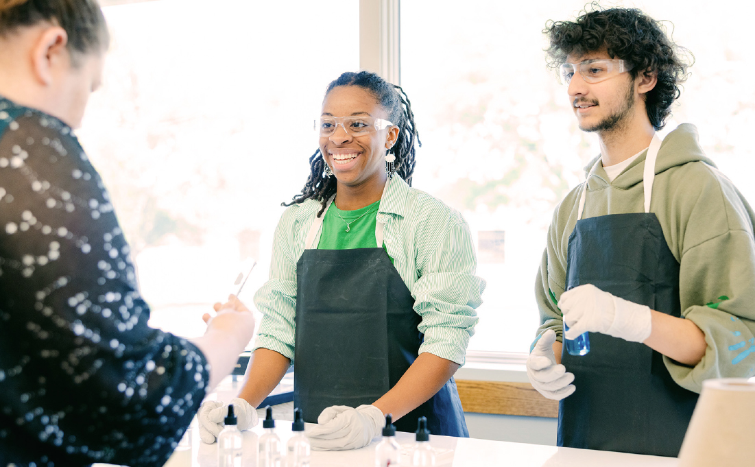 Two students watch a teacher give a chemistry demonstration.
