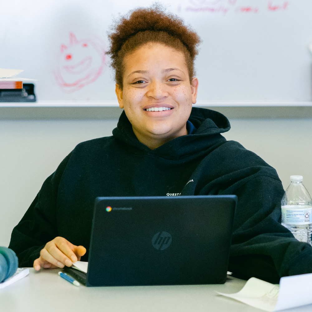 Student with laptop computer smiling at camera.