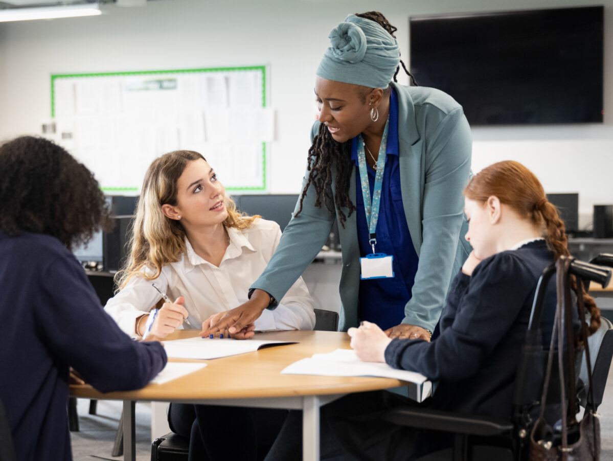 Students in a work room talking to a teacher.